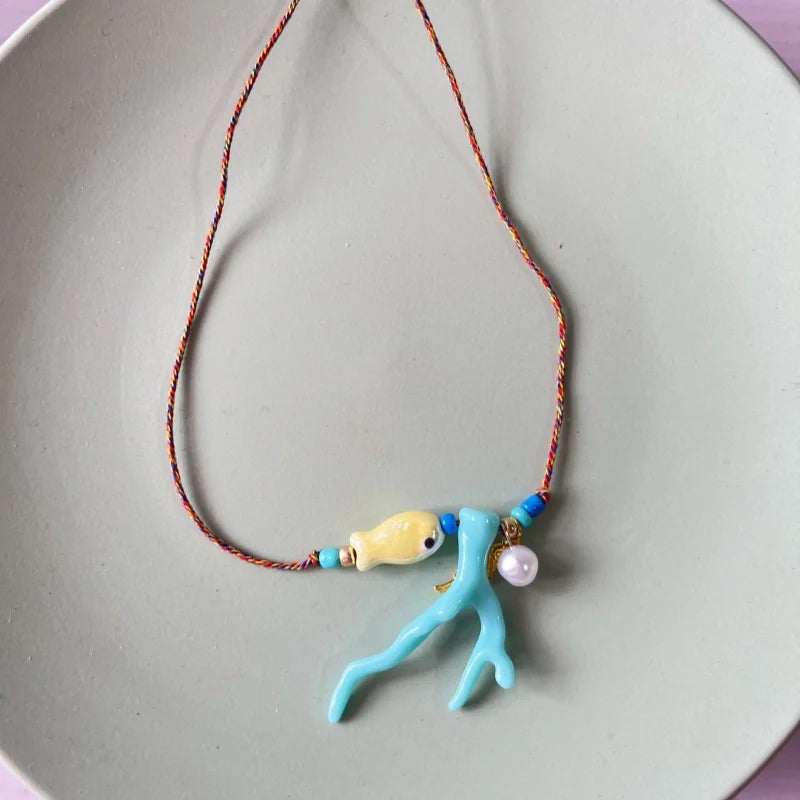 Halskette mit Korallenanhänger und blauem Fisch